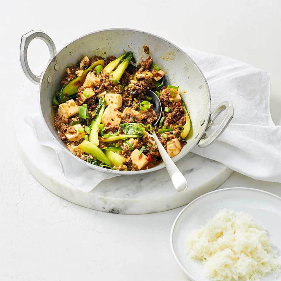 Hackfleisch mit Pak Choi und Tofu in scharfer Sauce angemacht in einer Pfanne, neben einer Schale Reis.