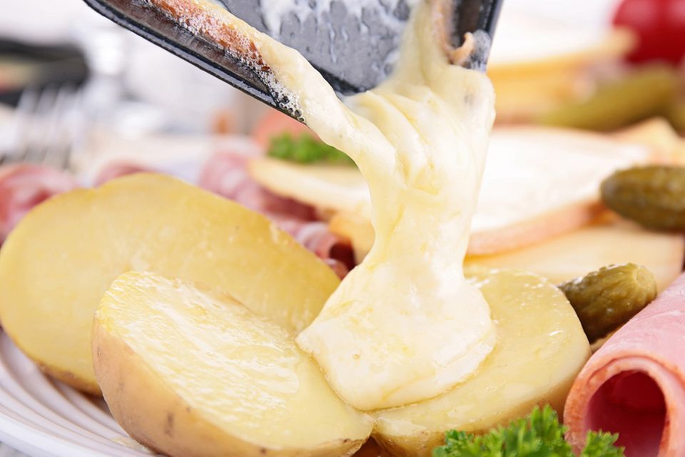 Geschmolzener Raclette-Käse aus dem Pfännchen mit Kartoffeln