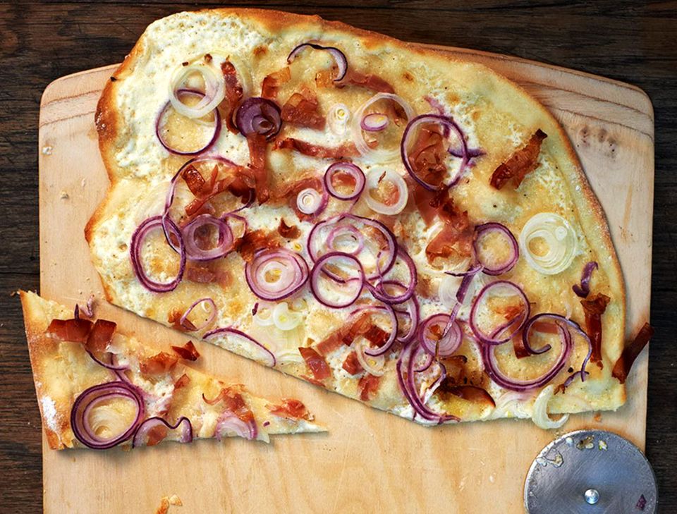 Dünner knuspriger Brotteig, belegt mit Crème fraîche, Zwiebeln und Speck Dünner knuspriger Brotteig, belegt mit Crème fraîche, Zwiebeln und Speck