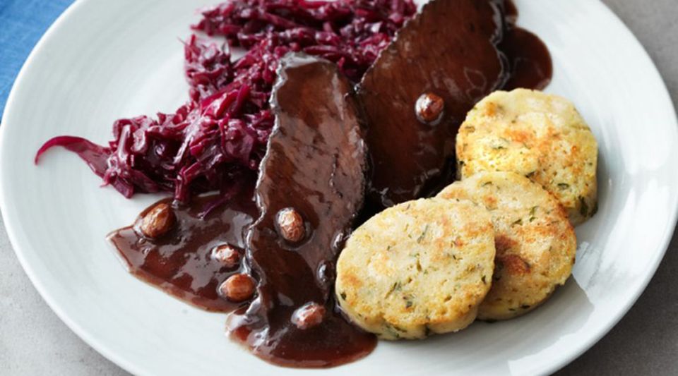 Sauerbraten: serviert mit Rotkohl, Knödeln und würziger Sauce Sauerbraten: serviert mit Rotkohl, Knödeln und würziger Sauce