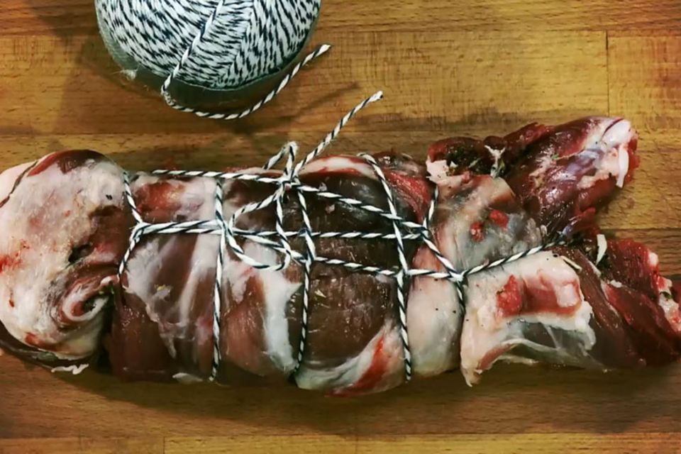 Lammbraten wird mit frischen Kräutern gewürzt.