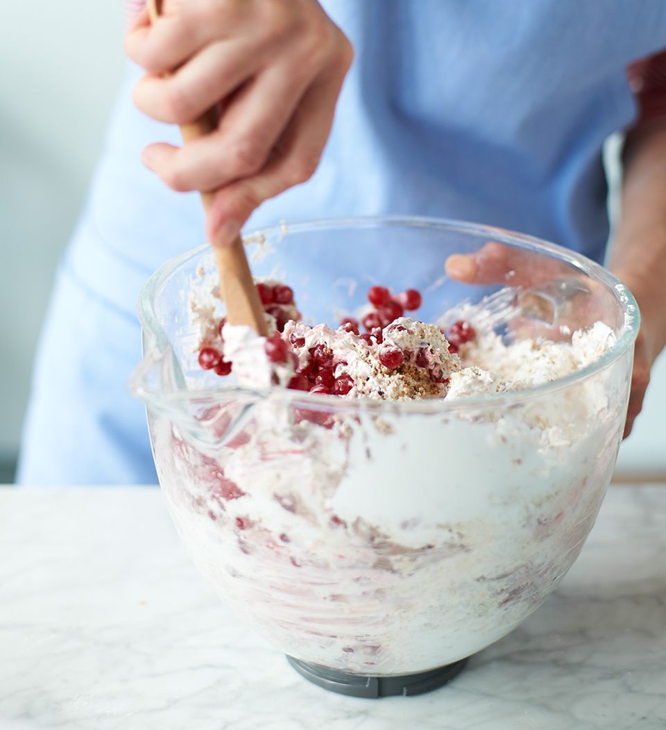 Mandeln und Johannisbeeren mit einem Kochlöffel unter Eischnee heben Mandeln und Johannisbeeren mit einem Kochlöffel unter Eischnee heben