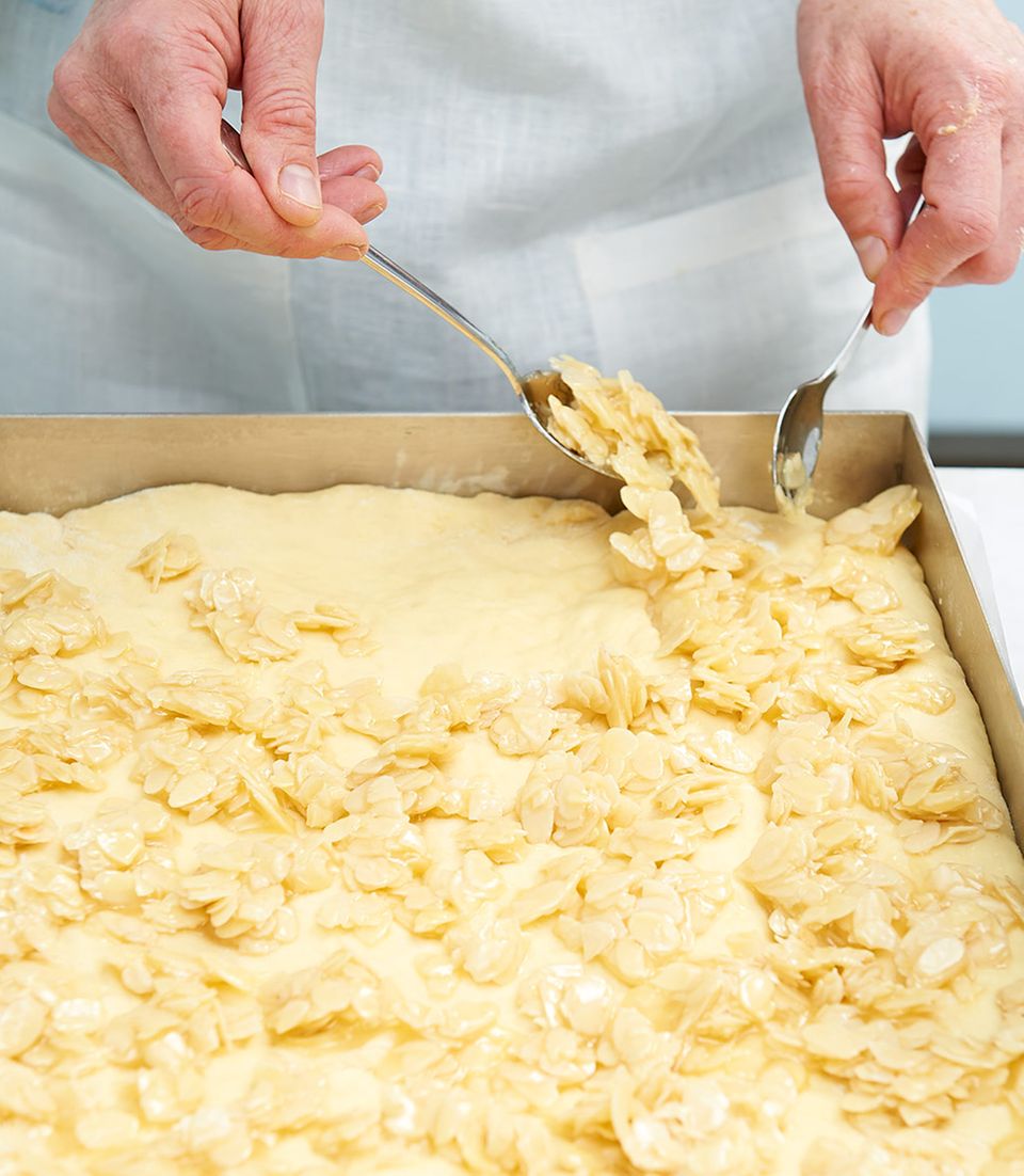 Mandelbelag für Bienenstich auf Kuchenteig verteilen Mandelbelag für Bienenstich auf Kuchenteig verteilen