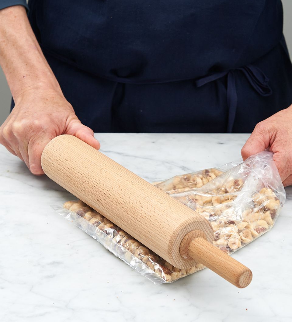 Haselnüsse in einem Gefrierbeutel mit einem Rollholz zerkleinern Haselnüsse in einem Gefrierbeutel mit einem Rollholz zerkleinern