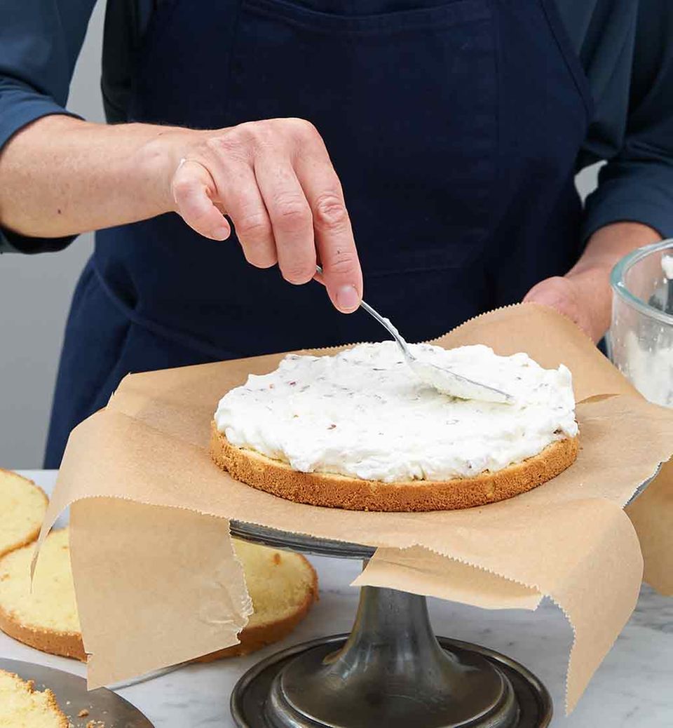 Nussahne mit dem Löffelrücken auf den Biskuitboden streichen Nussahne mit dem Löffelrücken auf den Biskuitboden streichen