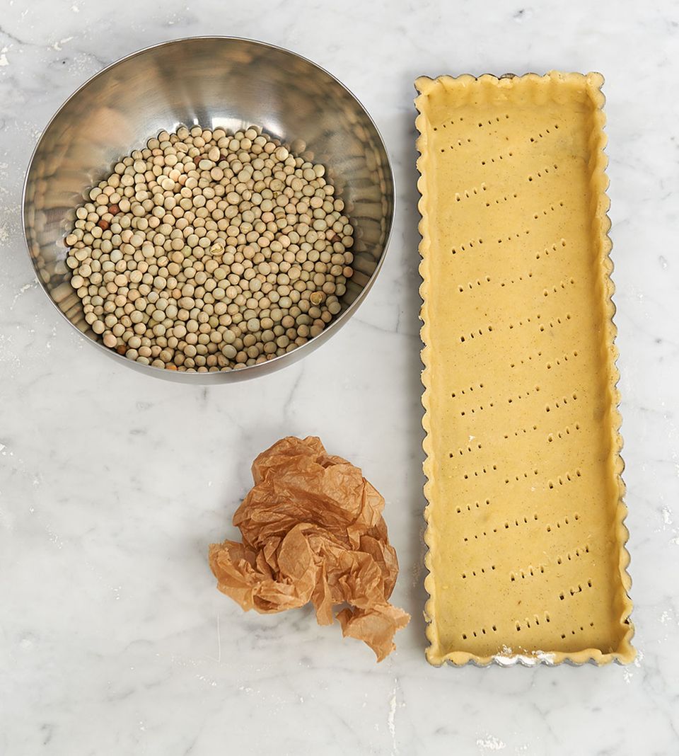 Startklar zum Blindbacken: Teig in der Tarteform mit Hülsenfrüchten und zerknülltem Backpapier Startklar zum Blindbacken: Teig in der Tarteform mit Hülsenfrüchten und zerknülltem Backpapier