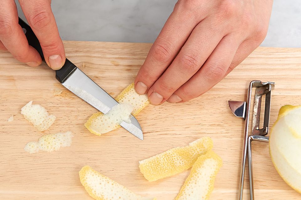Weiße Haut mit dem Messer von Zitronenschale entfernen