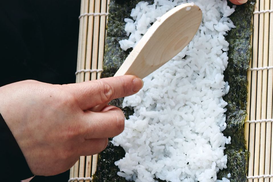 Sushirollen werden mit einer Bambusmatte in Form gebracht.