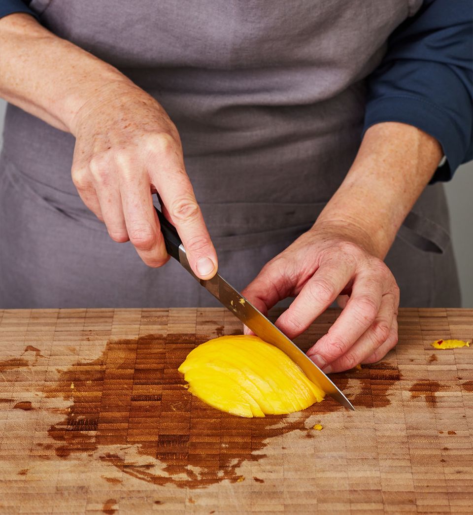 Für die Garnitur eine Mangohälfte mit einem scharfen Küchenmesser längs in dünne Spalten schneiden. Für die Garnitur eine Mangohälfte mit einem scharfen Küchenmesser längs in dünne Spalten schneiden.