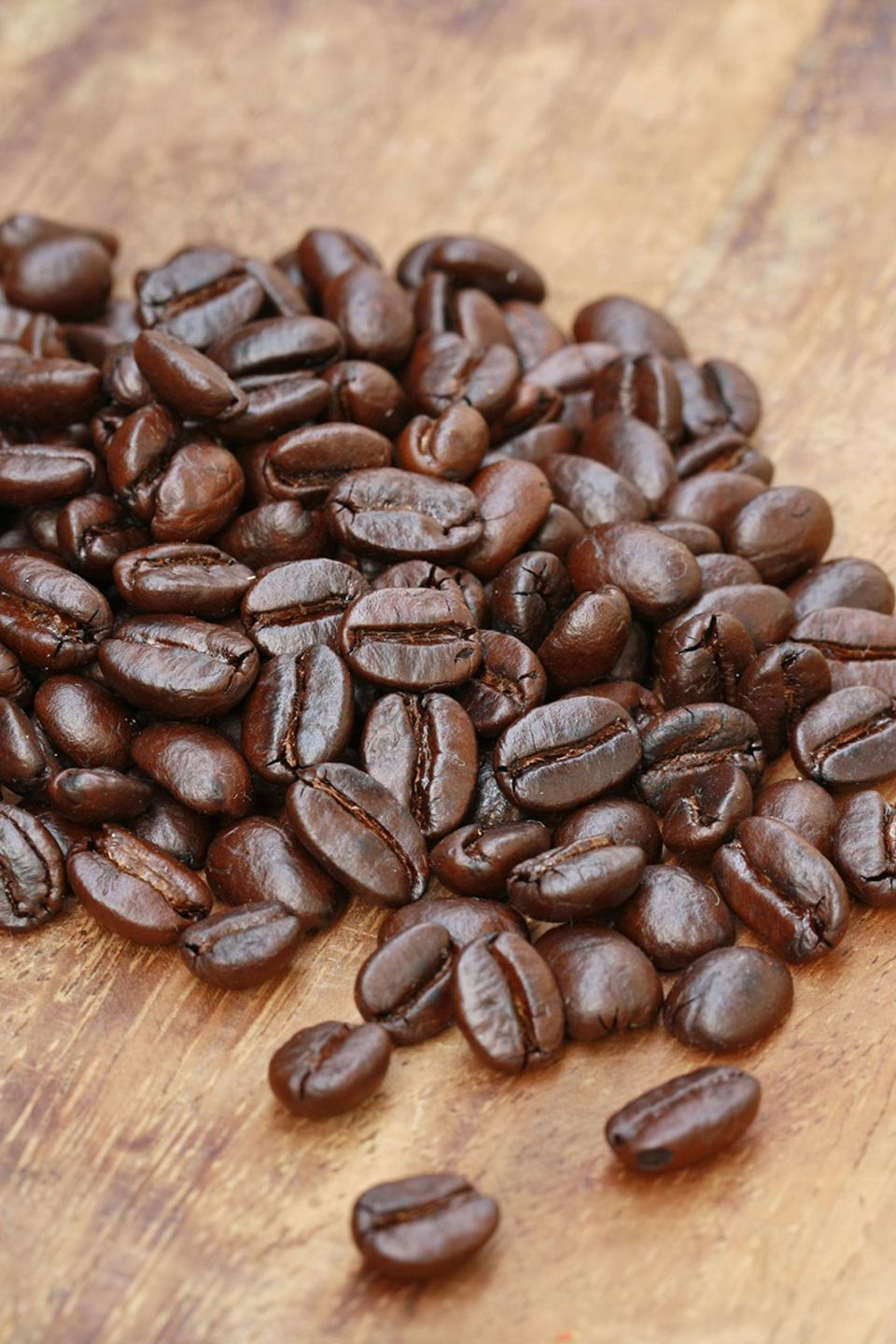 Geröstete Kaffeebohnen auf Holzplatte Geröstete Kaffeebohnen auf Holzplatte