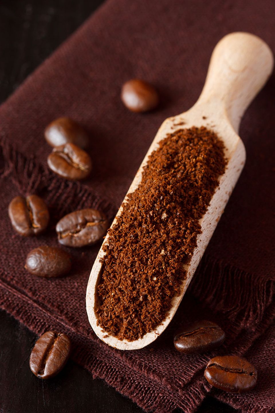 Gemahlener Kaffee auf einem Holzlöffel plus Kaffeebohnen Gemahlener Kaffee auf einem Holzlöffel plus Kaffeebohnen