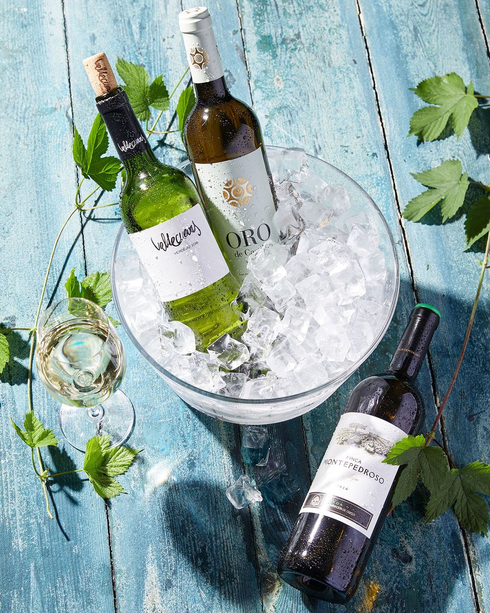 Weißwein Verdejo in Flaschen in einem Kühler mit Eiswürfeln und Weißwein im Glas Weißwein Verdejo in Flaschen in einem Kühler mit Eiswürfeln und Weißwein im Glas
