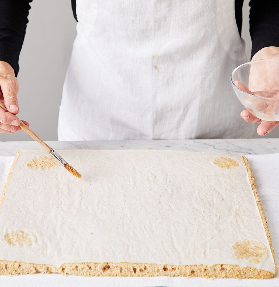 Backpapier wird mit Wasser bepinselt Backpapier wird mit Wasser bepinselt
