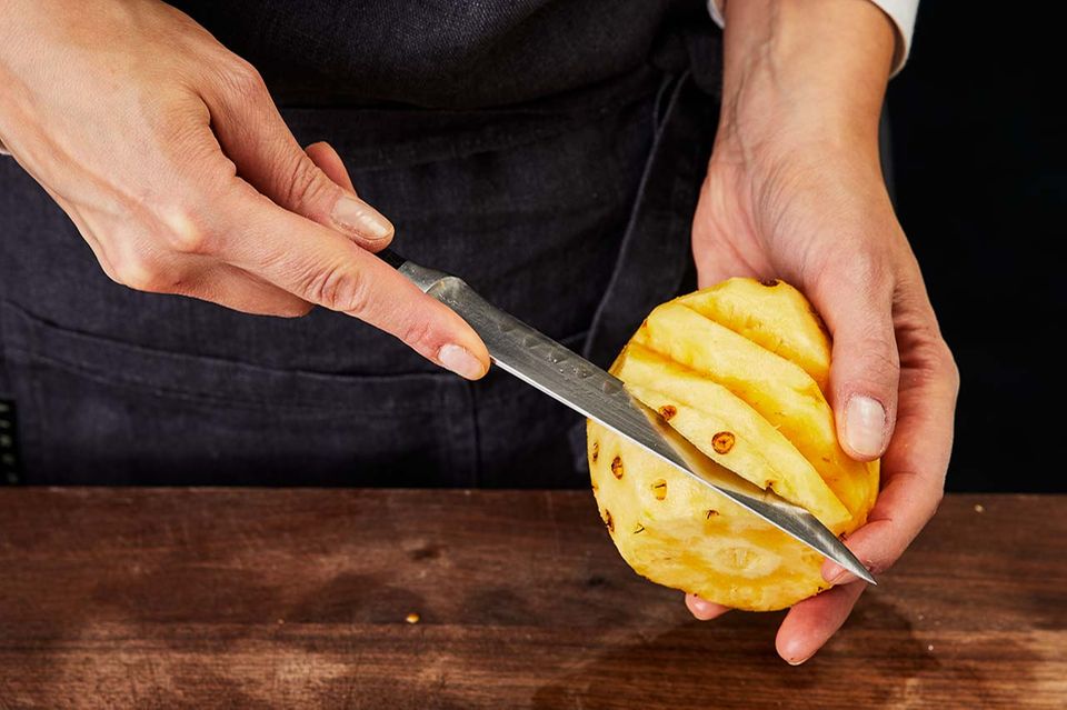 Augen aus dem Fruchtfleisch der Ananas herausschneiden Augen aus dem Fruchtfleisch der Ananas herausschneiden
