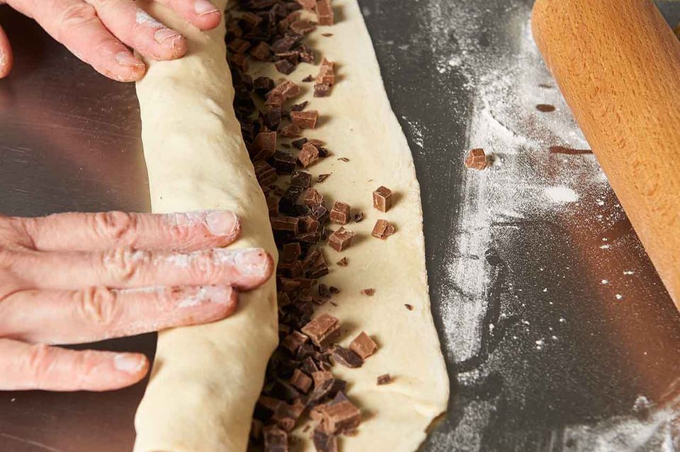 Zubereitung gefüllte Hefeschnecken: Teig mit Schokolade bestreuen und rollen