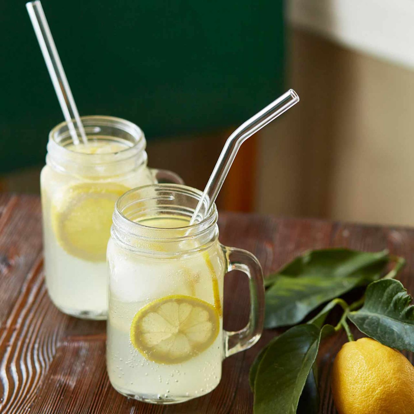 wiederverwendbare Trinkhalme aus Glas, Limonade mit Zirtonenscheiben in Einweggläsern serviert,