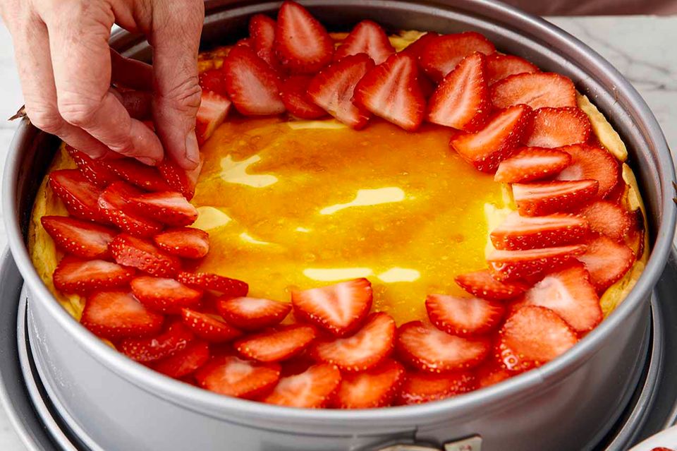 Erdbeerstücke auf dem Käsekuchen verteilen