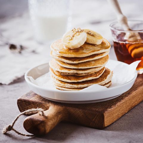 gesunde Pancakes aufeinander gestapelt mit Banane on Top auf weißem Teller