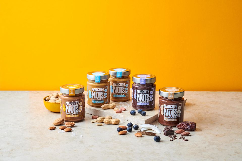 Nussmus-Sortiment von Naughty Nuts vor gelber Wand