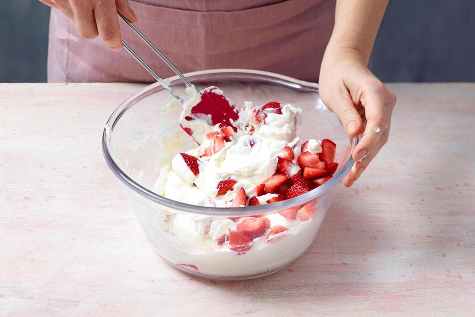 Übrige Sahne vorsichtig mit einem Teigschaber unter die Erdbeeren heben.