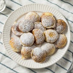 Einfach unwiderstehlich: original holländische Poffertjes – serviert mit einem Stück Butter und viel Puderzucker.