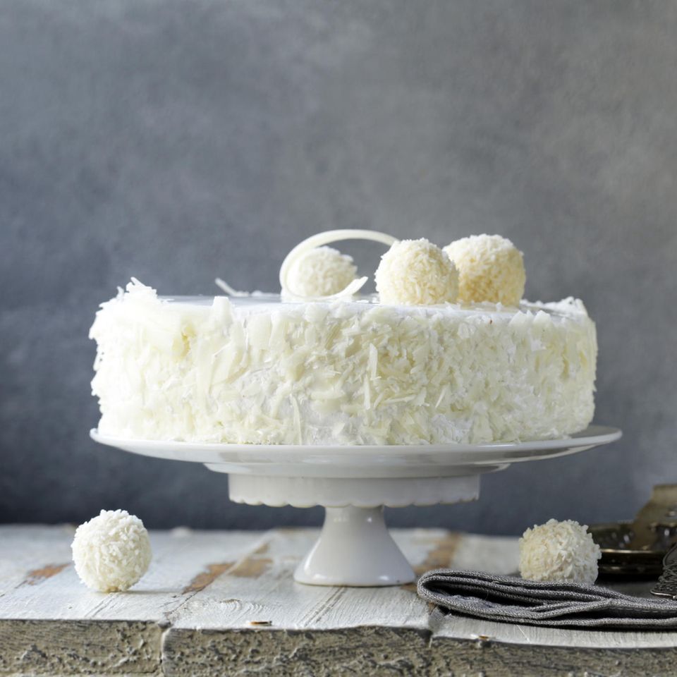 Weiße Torte mit Kokosraspeln am Rand und mit Raffaellos obendrauf