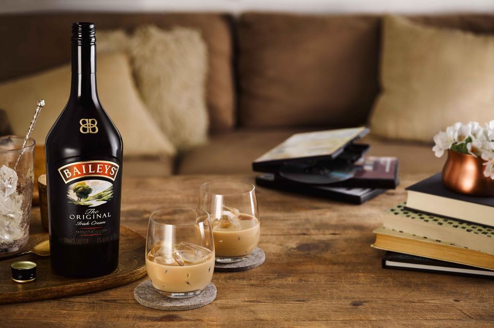 Baileys Original Irish Cream in der Flasche und in zwei Gläsern mit Eiswürfeln