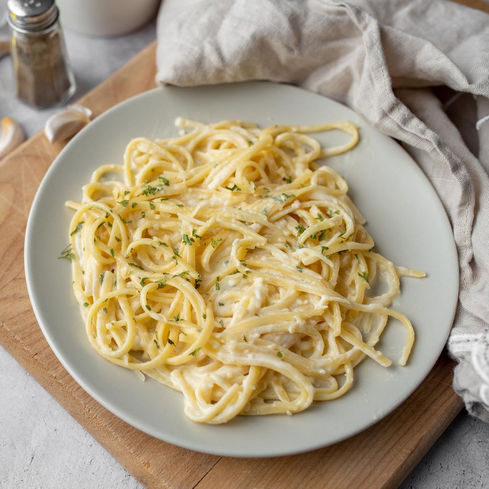 Gorgonzola Sauce mit Spaghetti auf hellem Teller und Holzbrett