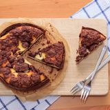 Angeschnittener veganer Russischer Zupfkuchen auf einem Holzbrett neben Kuchengabeln auf einem blau-weiß-karrierten Geschirrtuch