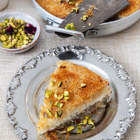 Ein Stück türkische Künefe aus Engelshaar mit Mozzarella auf einem silbernen Servierteller bestreut mit Pistazien.