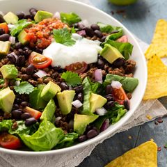 Taco-Salat mit viel Gemüse in einer Schale, zum Beispiel Bohnen, Avocado, Tomaten und Hackfleisch mit Tortilla-Chips angerichtet
