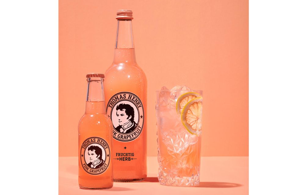Thomas Henry Pink Grapefruit in kleiner und großer Flasche vor orangenem Hintergrund