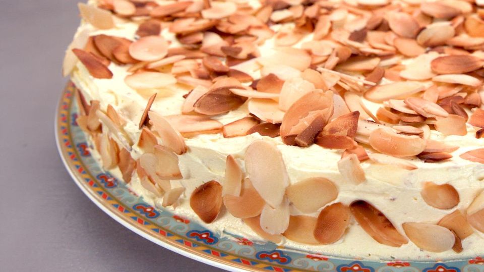 Eine flache cremige Torte, die mit vielen Mandeln bestreut ist