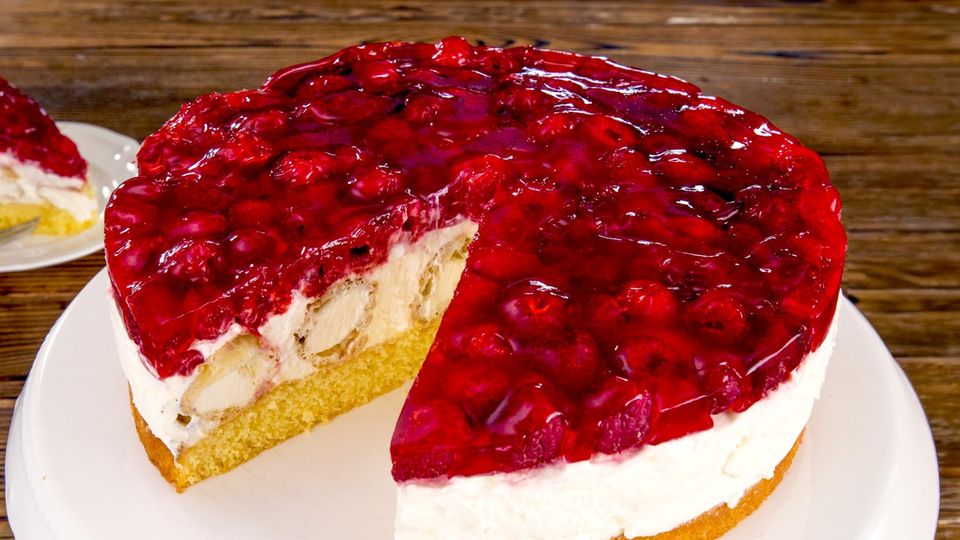Eine angeschnittene HimbeerTorte, in deren Füllung man Windbeutel sieht